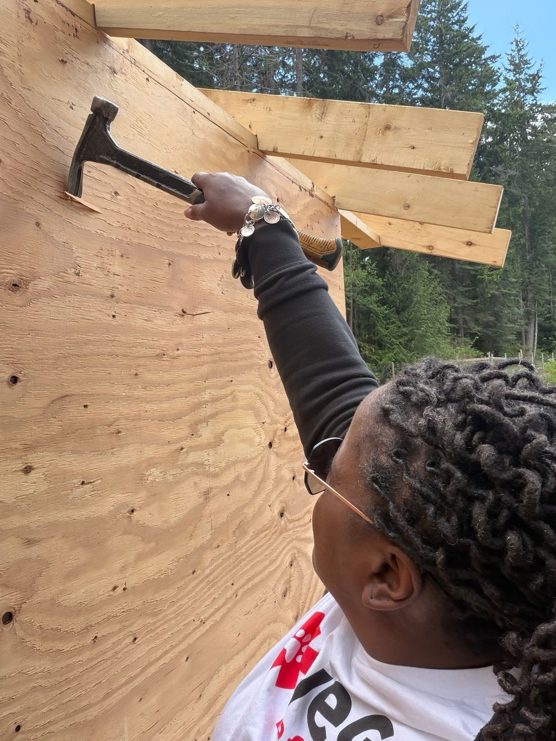 Dr. Atkinson-Spinks hammering a rafter into place on one of the new buildings